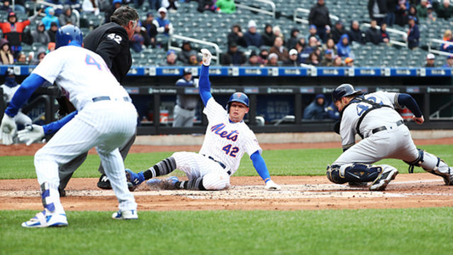 Brandon Nimmo #9 of the New York Mets scores against Jett Bandy #47 of the Milwaukee Brewers in New York City.