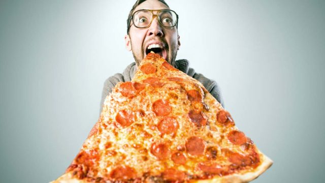 Man eating giant slice of pizza, Getty