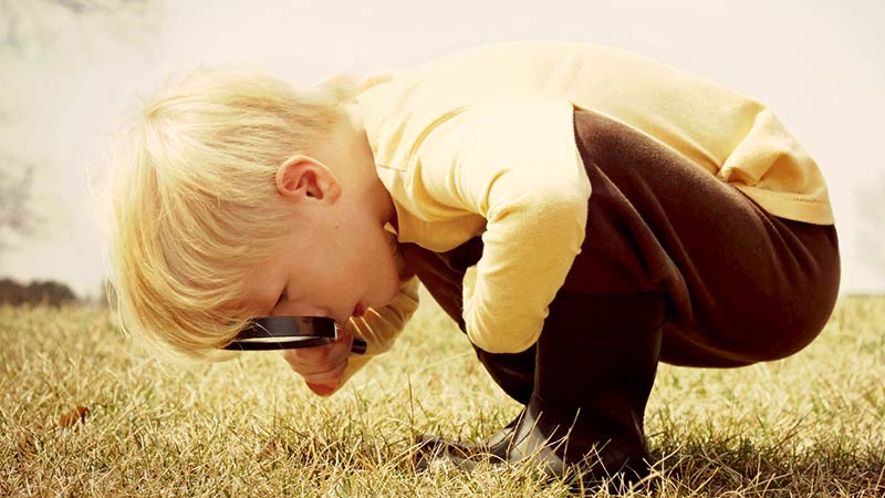 A child looking through a magnifying glass. Pic: Getty