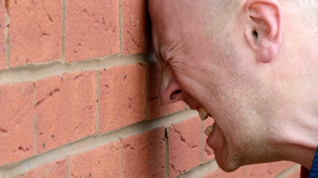 A man bangs his head on a wall. Pic: Getty