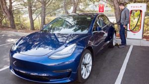 A man charges his Tesla Model 3 at a supercharger station. Pic: Getty