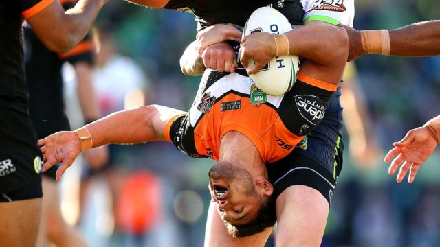 David Nofoaluma of the Tigers is held upside down by Blake Austin of the Raiders in round 22 of the NRL. Pic: Getty