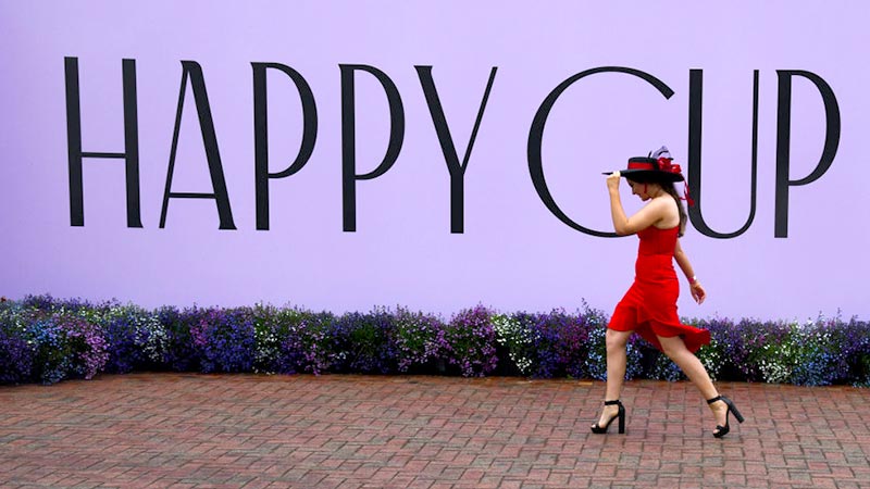 A racegoer arrives for a rainy Melbourne Cup Day at Flemington in Melbourne this morning. Pic: Getty