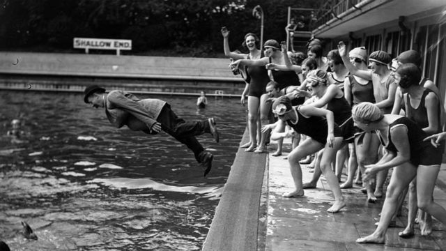 women pushing man in pool, Getty