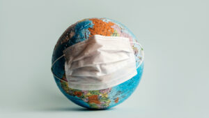 Globe made of jigsaw puzzles with a protective medical mask